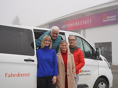 Vier Personen vor einem Fahrzeug
